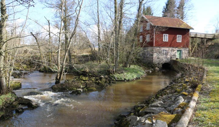 Småskalig vattenkraft, vatten som flödar i förgrunden och ett hus i bakgrunden.