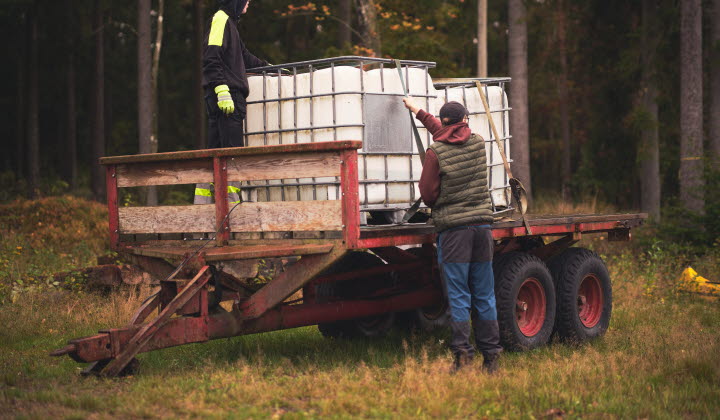 En bonde spänner fast vattentankar på ett traktorsläp.