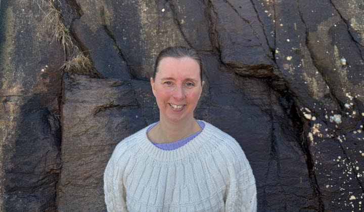 Kristina Jacobsson, kvinna i vit tröja framför en klippvägg