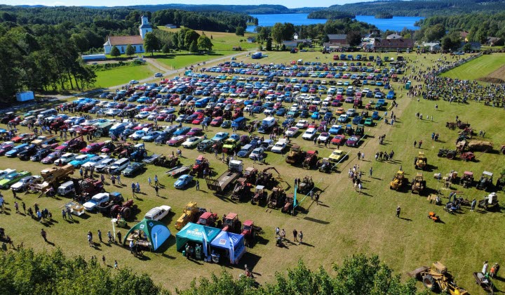 Motorfest i Karl-Gustav. Rader av parkerade bilar i olika färger ute på en äng.