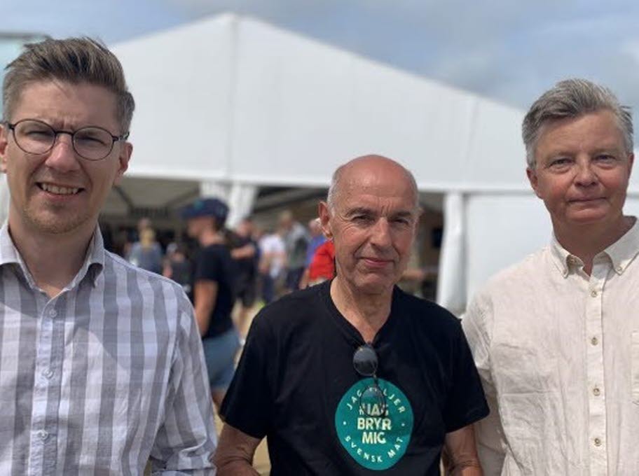 Tre män på en utomhusmässa.