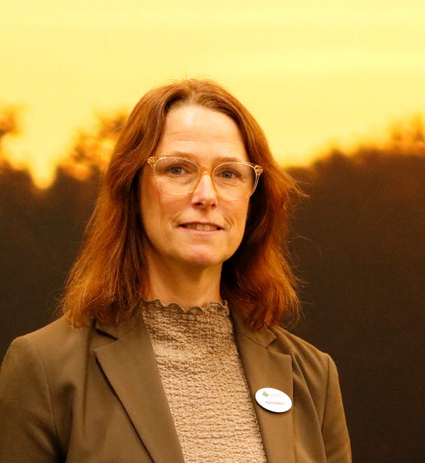 Kvinna i brun kavaj med brunt hår.