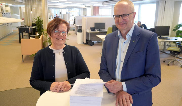 Åsa Odell och Palle Borgström står vid ett bord med en hög av papper.